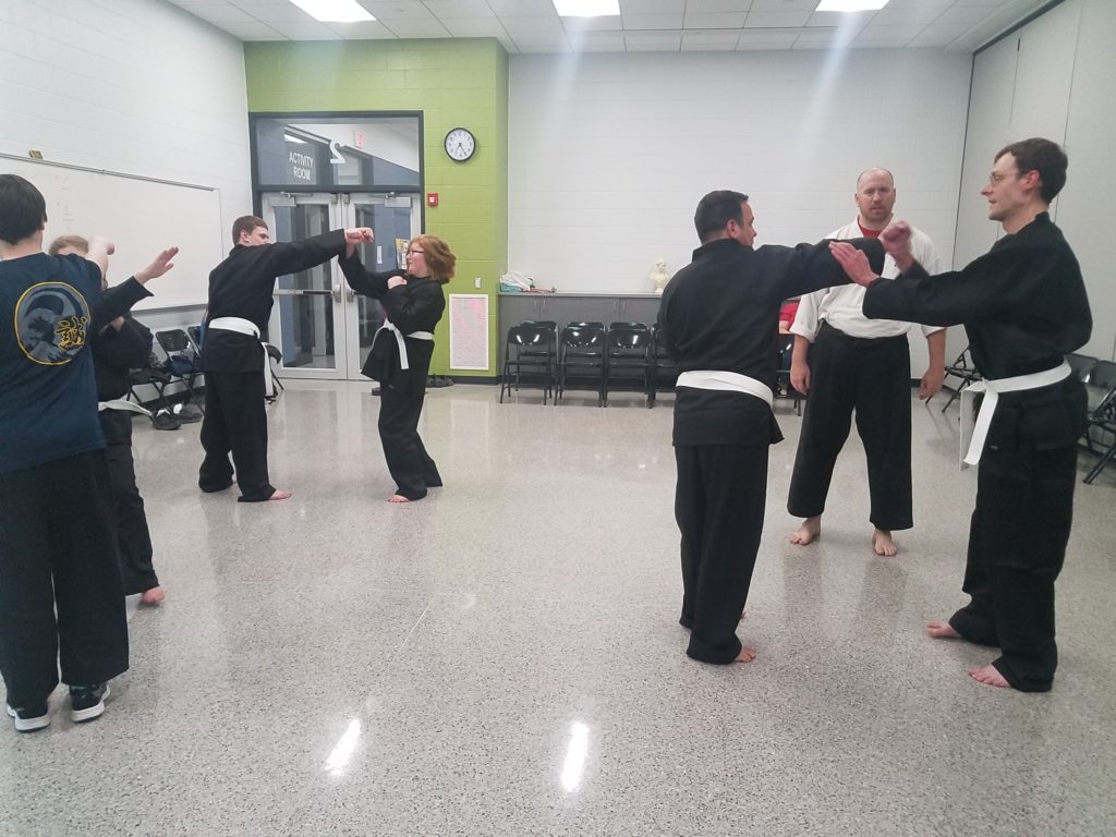 Adults and teens practice advanced techniques in karate class